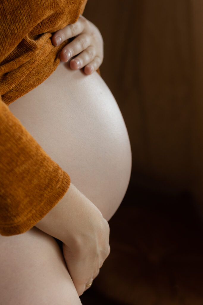 Nackter Schwangerschaftsbauch von der Seitenansicht.