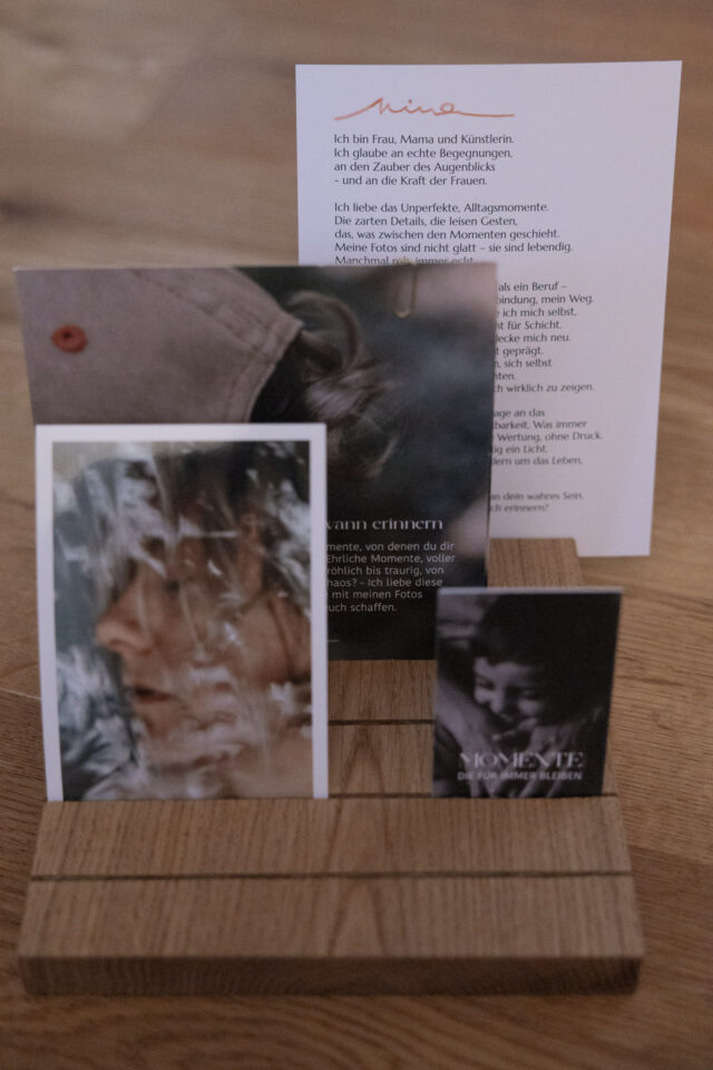 Ein Holzaufsteller mit Fotos, Texten und Visitenkarten.