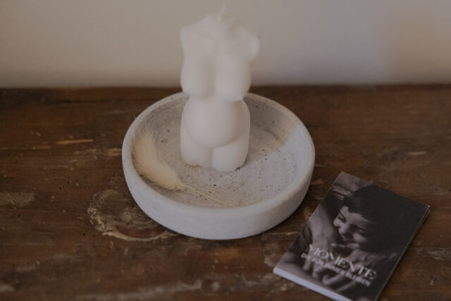 Eine Kerze, geformt zu einem Frauenkörper. Daneben liegen Visitenkarten.