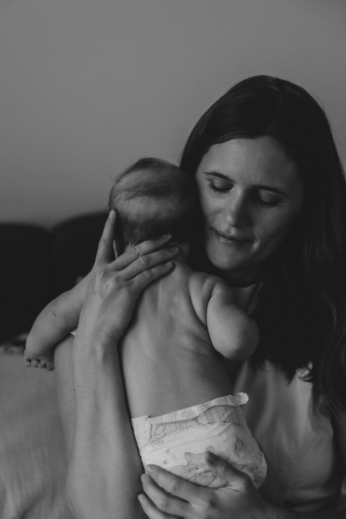 Eine Frau, die liebevoll ihr Baby in Windel hochhebt und an sich drückt. Schwarz-Weiß-Bild.