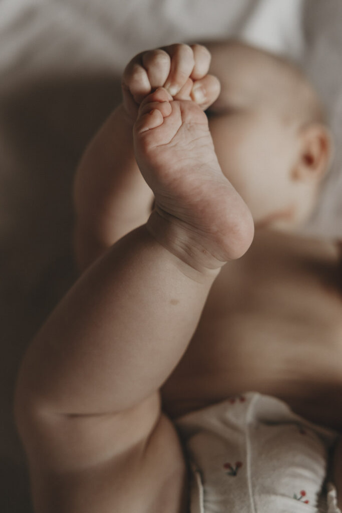 Baby, das nach seinen Füßchen und Zehen greift.