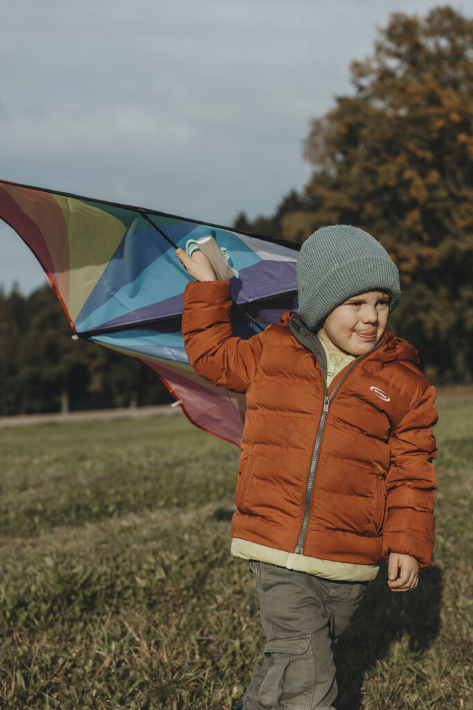 Kind, das einen Drachen über den Kopf hält.