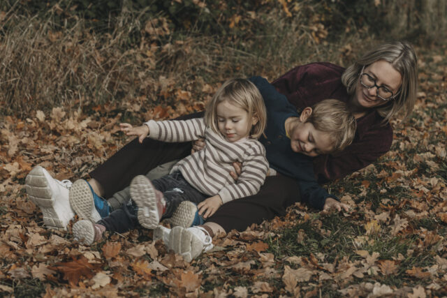 Mama mit ihren beiden Kindern zwischen den Füßen. Sie singen, lachen und bewegen sich gemeinsam.