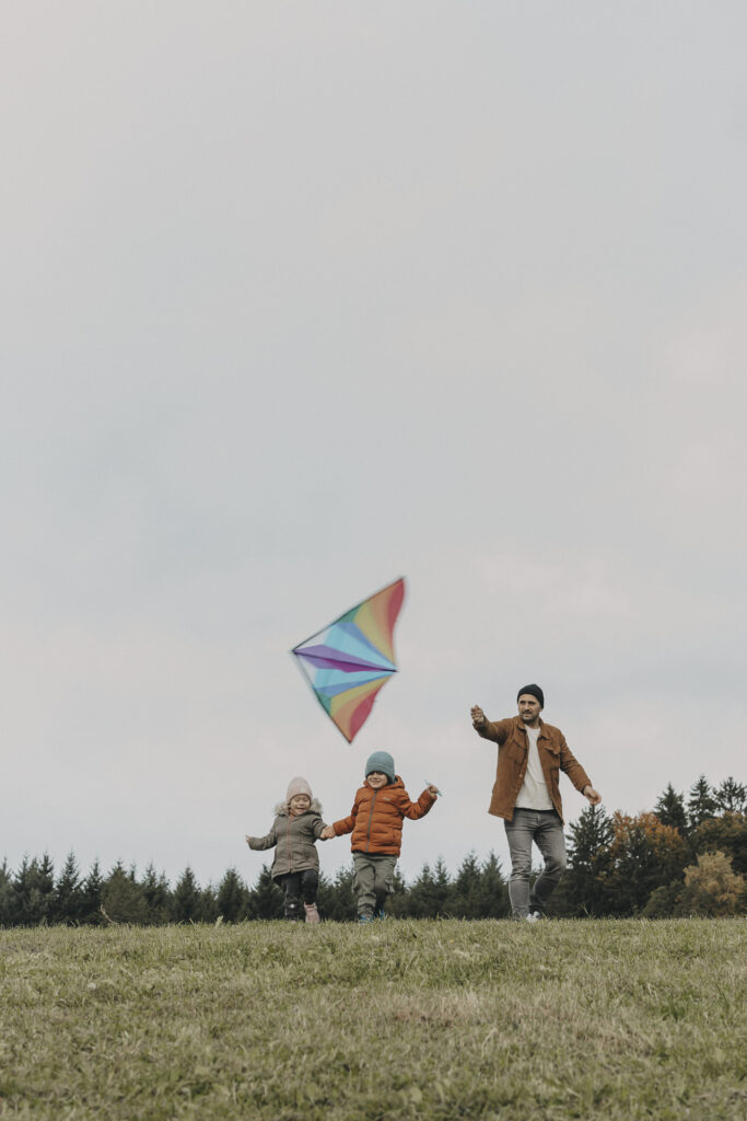 Vater mit seinen Kindern beim Drachensteigen.