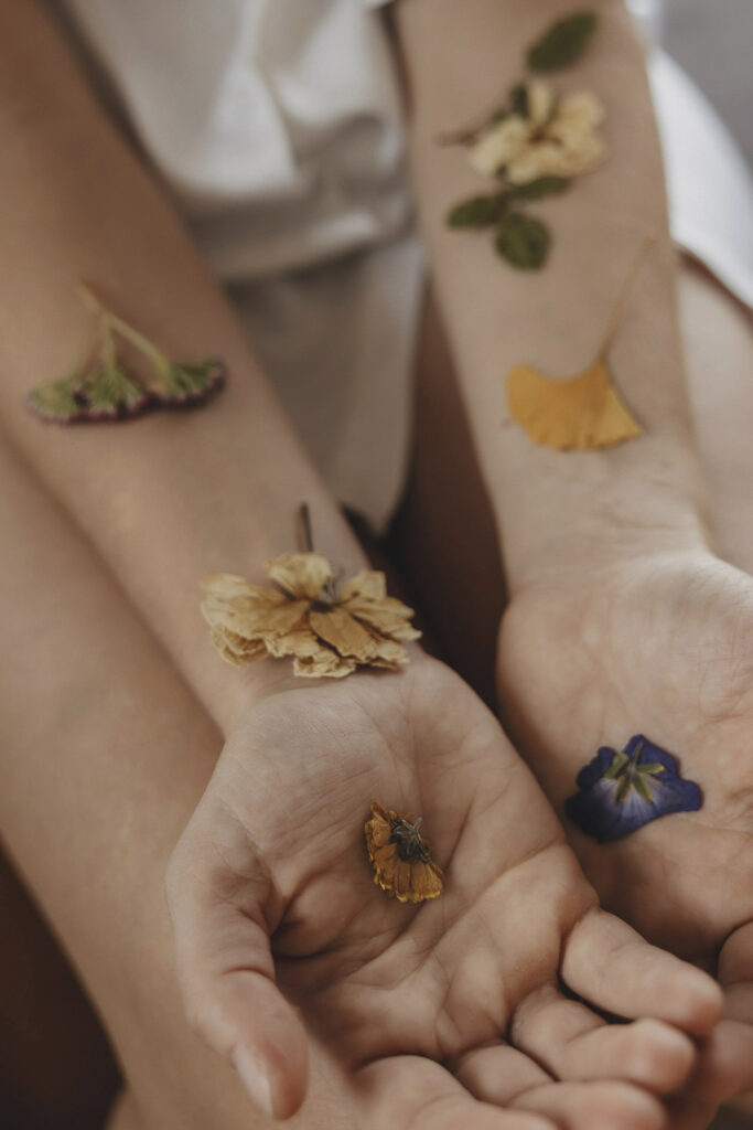 Handinnenflächen einer Frau mit getrockneten Blumen darauf.