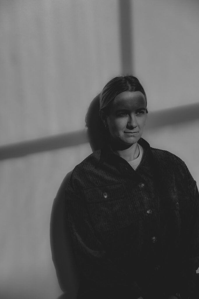 Frauenportrait. Der Schatten eines Fensters kreuzt sich in ihrem Gesicht. Schwarz-Weiß-Bild.