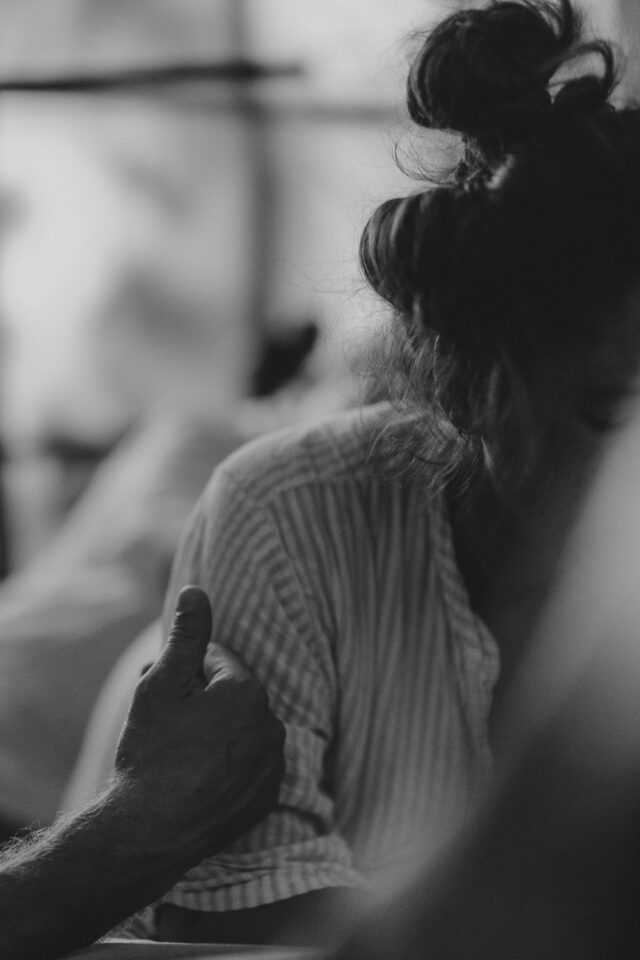 Man erkennt eine Gebärdende. Eine Männerhand berührt sie sanft. Schwarz-Weiß-Bild.