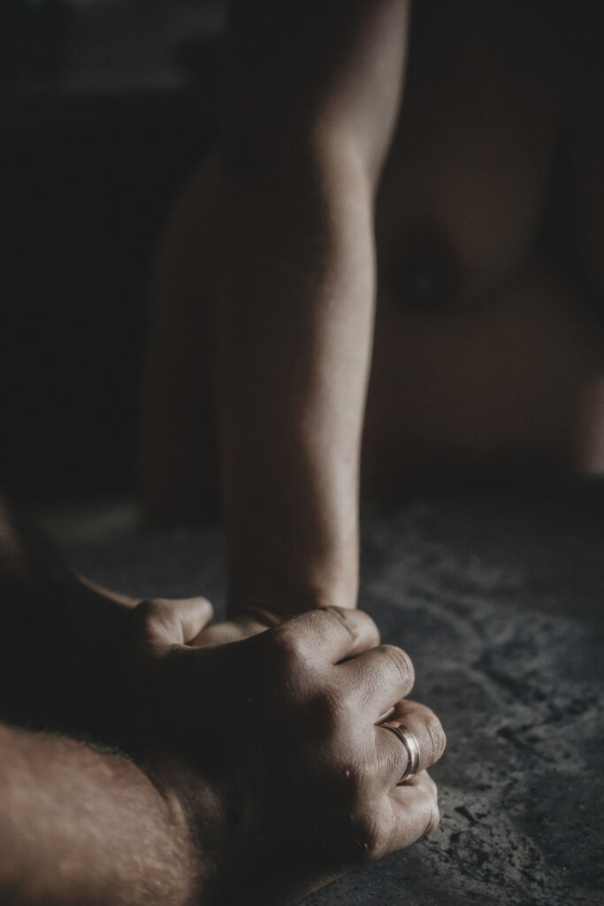 Männerhand, die liebevoll die Hand seiner Frau hält.