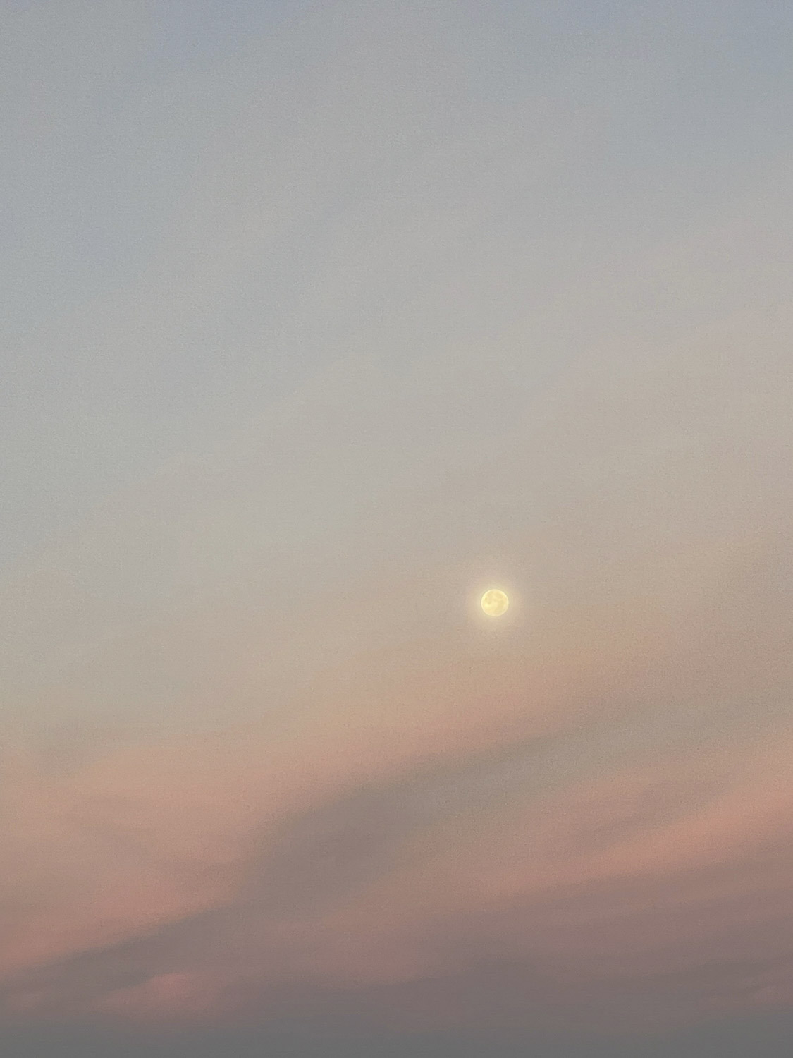 Vollmond im Abendlicht, der Himmel färbst sich von hellblau, bis orange, rosa und lila.