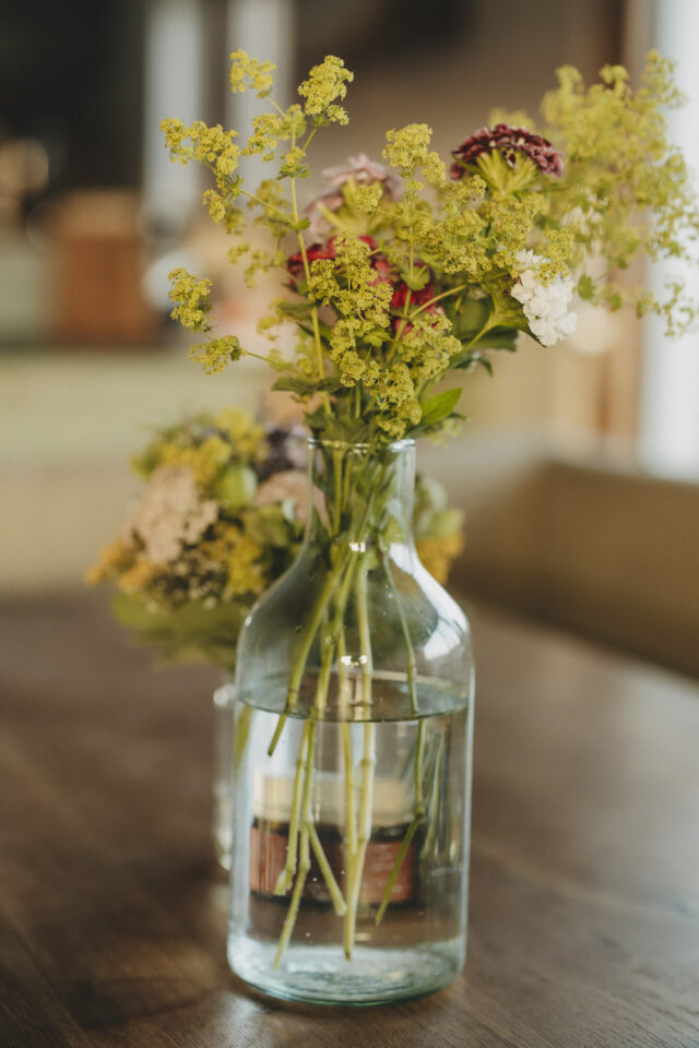 Ein Strauß Frauenmantel steht in einer Vase auf dem Tisch.