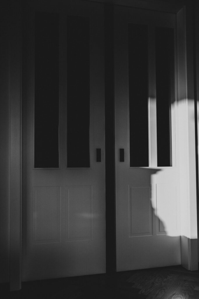 Schwarz-Weiß-Bild. Schiebetür, die sich in der Mitte leicht öffnet.