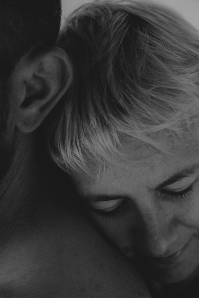 Schwarz-Weiß-Bild. Frauenkopf angelehnt an der Schulder und am Rücken eines Mannes.