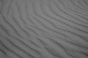 Schwarz-Weiß-Bild. Feiner Sandstrand mit Wellen, die durch den Wind entstanden sind.