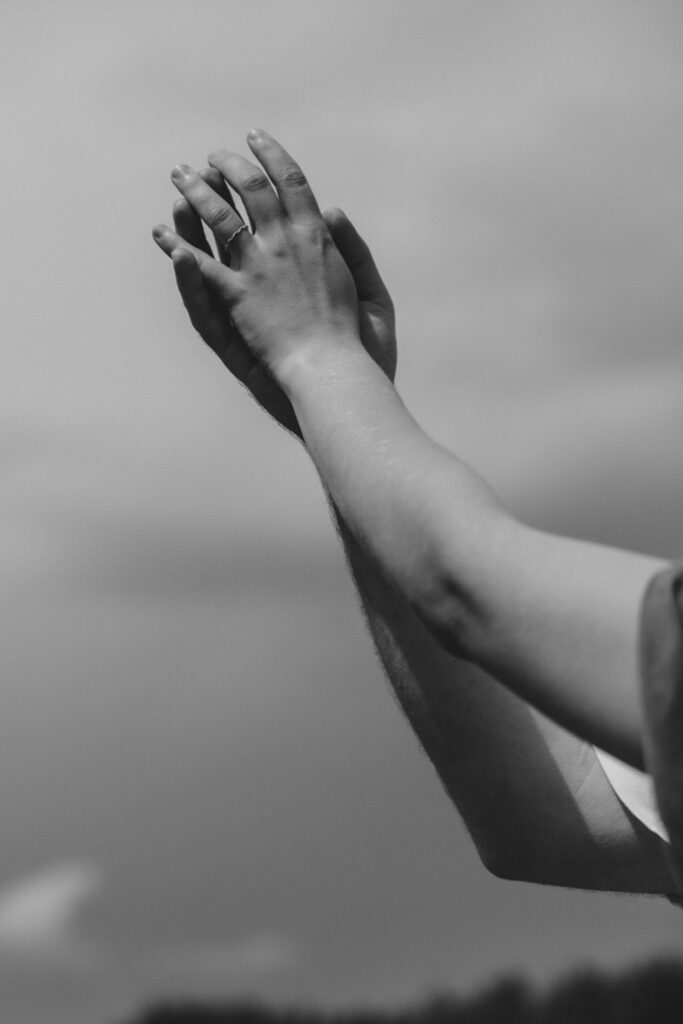 Schwarz-Weiß-Bild. Berührende Hände einer Frau und eines Mannes, in die Luft gestreckt.