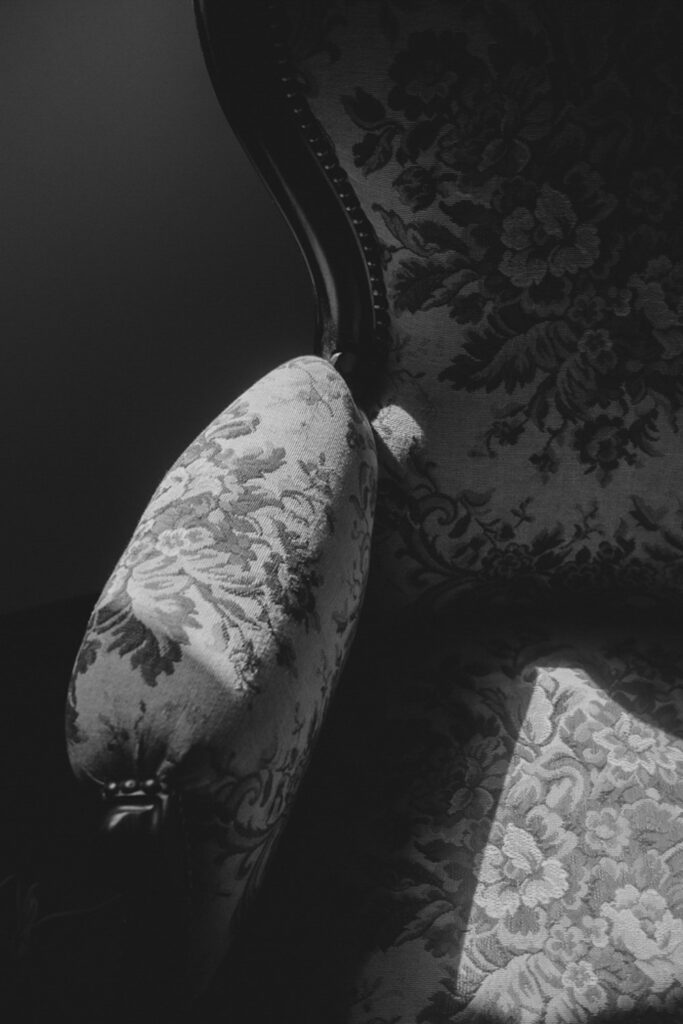 Schwarz-Weiß-Bild. Lehne eines alten Stuhls. Ein Lichtstrahl streift den Stuhl und wirkt wie eine Berührung.