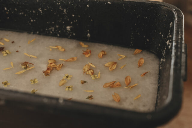 Wasser mit weißer Flüßigkeit und Blüten in einem großen Topf.