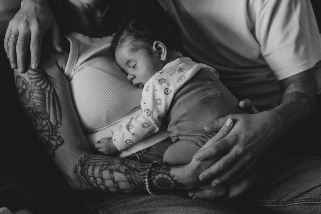 Schwarz-Weiß-Bild. Baby auf der Brust der Mutter. In den Armen von Mama und Papa.