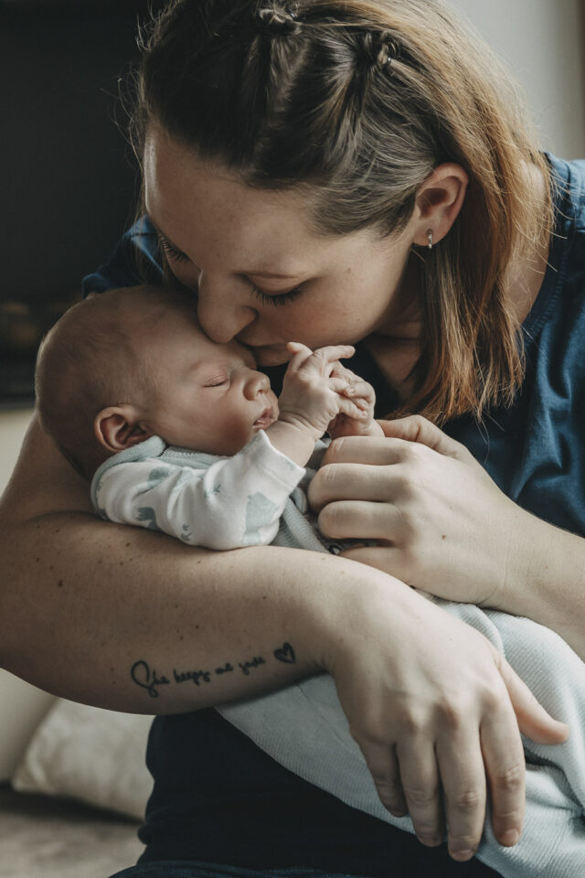 Mutter küsst ihr Baby auf die Stirn.