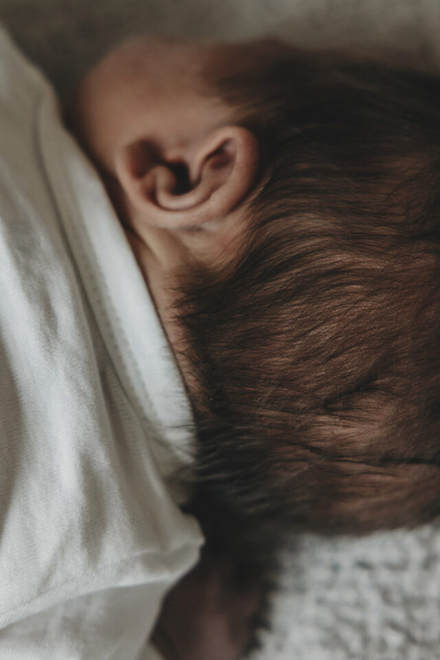 Babykopf von hinten, man erkennt nur Ohren und Haare.