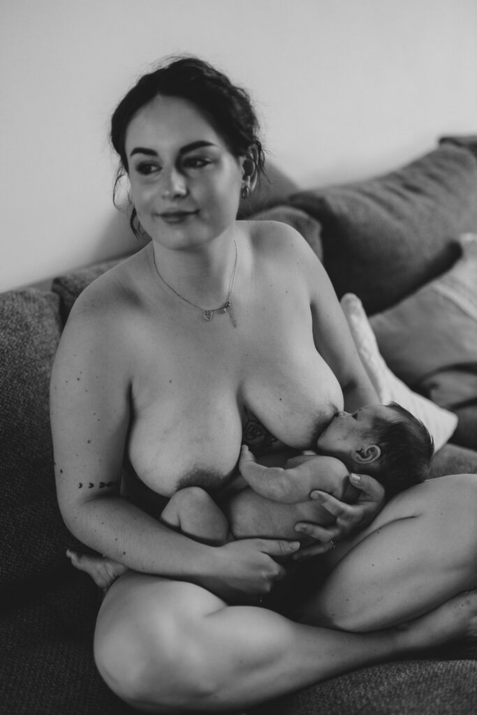 Nackte Frau mit nacktem Baby, das gerade gestillt wird. Schwarz-Weiß-Bild.