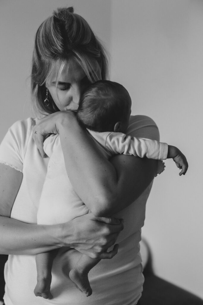 Frau umarmt und küsst ihr kleines Baby. Schwarz-Weiß-Bild.