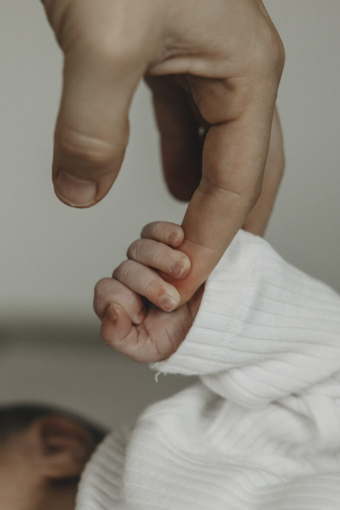 Hand eines Babys das den Finger der Mama ganz fest hält.
